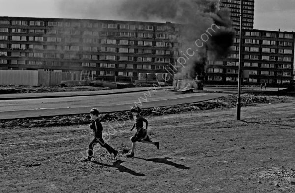 Children play as barricades burn